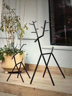 two metal sculptures sitting on top of a wooden floor next to a potted plant