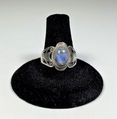 Cut-out sterling silver ring with white Moonstone cabochon in double beaded bezel. Stone has nice play of color showing brilliant blue. Marked 925 for sterling silver.  Very good condition. Silver has small scratches typical of vintage jewelry. They can be polished out if you prefer but they don't hurt the look of the ring. The stone really steals the show. Sterling Silver Oval Cabochon Moonstone Ring, Oval Cabochon Moonstone Ring In Sterling Silver, Adjustable Oval Nickel-free Moonstone Ring, Silver Moonstone Oval Cabochon Ring Stamped 925, Adjustable Cabochon Moonstone Promise Ring, Adjustable Oval Cabochon Moonstone Ring, Adjustable Moonstone Ring Stamped 925, Handmade Adjustable Oval Cabochon Moonstone Ring, Blue Moonstone Cabochon Ring