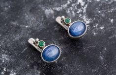 Kyanite Earrings set with Natural Kyanite in a cabochon cut & natural blue color, at size 10x8mm each, together with Natural Emerald at size 3mm each (6 Cts a pair).Solid 925 Sterling Silver ☞ made to last. Click here for ☞ Matching RingClick here for ☞ Matching PendantDetails:• Natural Kyanite (Africa) & Natural Emerald (Colombia)• Kyanite: 10x8mm each, 6 Cts total, cabochon cut• Emerald: 3mm each, 0.22 Cts, diamond cut• Lever Back Closure - "English Lock"• Dimensions: Length ≈ 15mm, Width ≈ 10 Blue Statement Earrings, Kyanite Earrings, Earrings Design, Matching Ring, Blue Kyanite, Matching Rings, Natural Emerald, Pierced Ears, Stone Earrings