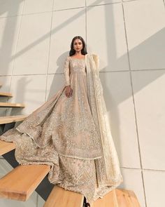 a woman in a long dress standing on some stairs