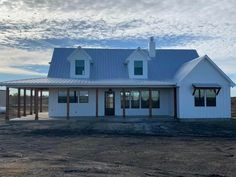 a large white house sitting on top of a dirt field