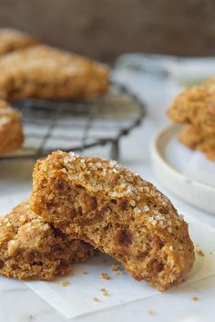 some cookies are sitting on top of white napkins and cooling rack with one broken in half