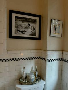 a white toilet sitting in a bathroom next to a framed picture on the wall above it