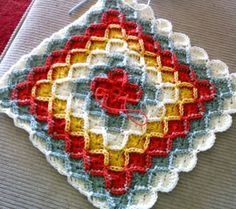 a crocheted dishcloth with red, yellow and blue squares on it sitting on a table