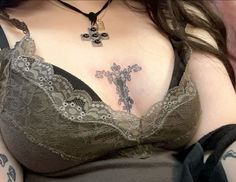 a woman with tattoos on her chest is wearing a bra and has a cross tattoo