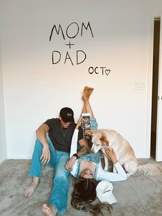 a man and woman laying on the floor with a dog next to them, reading a book