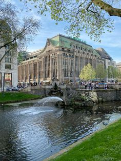 a large building sitting on top of a lush green field next to a river filled with water