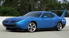 a blue sports car parked in front of some trees