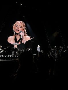 a woman standing on top of a stage holding a microphone in front of an audience