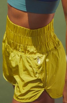 a woman in yellow shorts holding a tennis racquet