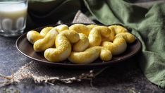 a plate full of yellow donuts next to a glass of milk on a table