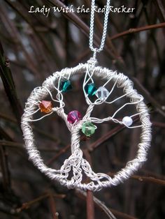 a white wire tree ornament hanging from a tree branch with colorful beads on it