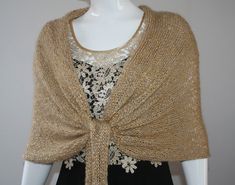 a mannequin wearing a gold knitted shawl with white flowers on it