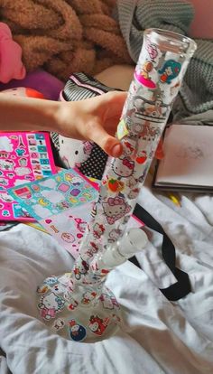 a person is holding a tube with hello kitty designs on it in front of a pile of stuffed animals