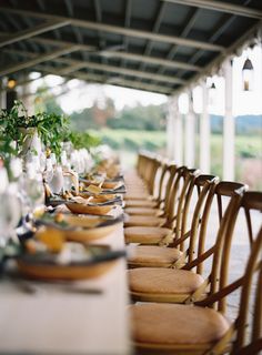 a long table with chairs and plates on it