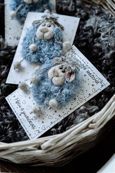 two teddy bears are sitting on some cards in a wicker basket with black yarn