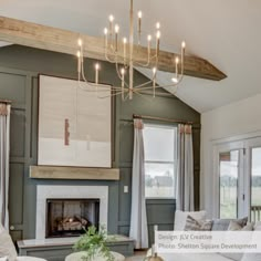 a living room filled with furniture and a chandelier hanging from the ceiling over a fire place