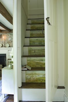 an open door leading to a set of stairs with paintings on the wall and wood flooring