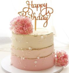 a birthday cake with pink and white frosting, topped with a gold happy birthday topper