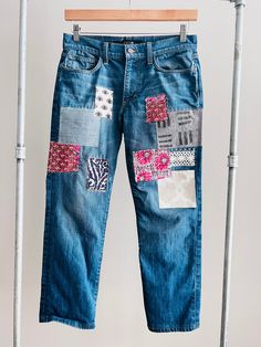 a pair of blue jeans with patchwork on them hanging from a clothesline rack