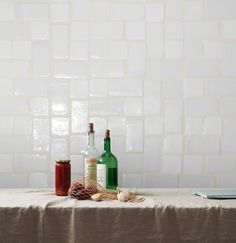 three bottles are sitting on a table in front of a white tile backsplash