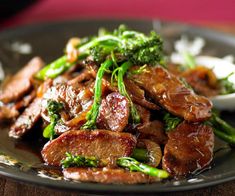 a black plate topped with meat and broccoli