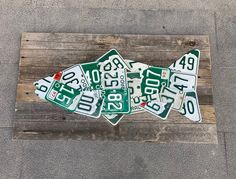 four green and white street signs sitting on top of a wooden bench