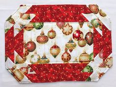 a red and white quilted placemat with christmas ornaments on the front, hanging from it's sides