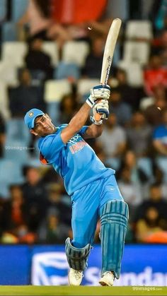 a man swinging a cricket bat on top of a field in front of a crowd