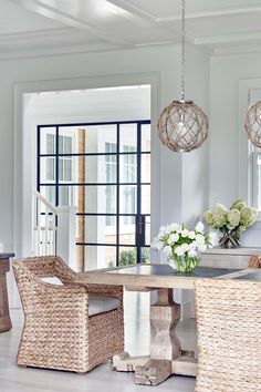 a dining room table with wicker chairs and vases on the table next to it