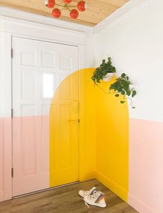 a pair of shoes sitting on the floor in front of a yellow and pink door