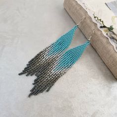 a pair of blue and silver beaded tassels hanging from a piece of fabric