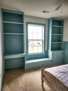 an empty bedroom with blue bookcases and a bed in it's corner