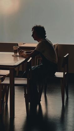 a man sitting at a wooden table in front of a projector screen on the wall