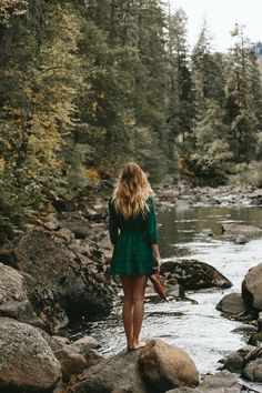 a woman standing on rocks in the middle of a river