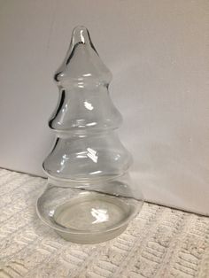 a clear glass christmas tree sitting on top of a white tablecloth covered floor next to a wall