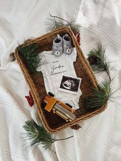 a basket filled with baby items on top of a white bed covered in pine needles