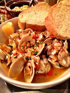 a bowl filled with clams and bread on top of a table