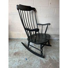 a black rocking chair against a white brick wall