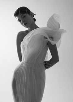 a woman in a white dress poses for the camera with her hands on her hips