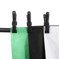 three black and white curtains hanging from a metal rod with two green and one white curtain