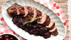 a plate with meat and cherries on it next to a bowl of cherries