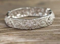 a wedding band with diamonds on top of wooden table next to other jewelry items and wood planks