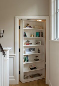 a white book shelf in the corner of a room next to a door and window