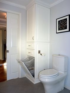 a white toilet sitting inside of a bathroom next to a wall mounted cabinet and door