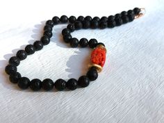 "I have handknotted with silk thread these black lava round  stones of 8,5 mm approx.  A beautiful raw coral is placed on one side of the necklace, between two bronze craft elements, which intensify the color contrast and make this item unique. The bronze rondelles are made by me. The coral comes from the Mediterranean Sea, more specifically from the island of Sardinia. It is a necklace that can be worn by both a man or a woman. Total lengh 17.8\" Details:  Total lenght: 17.8\"  (45 cm) black la Recycled Necklace, Organic Necklace, Sunburst Necklace, Cactus Necklace, Red Coral Necklace, Organic Jewelry, Black Stones, Nature Necklace, White Moonstone