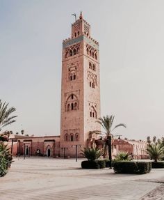 a tall tower with a clock on it's side in the middle of a courtyard