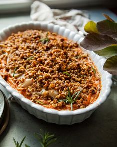 a casserole dish with meat and vegetables in it on a table next to a clock