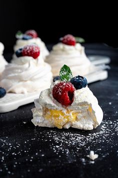 small desserts with berries and whipped cream on black table top, ready to be eaten