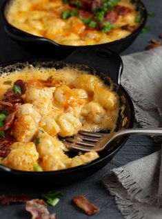 two black pans filled with macaroni and cheese on top of a table